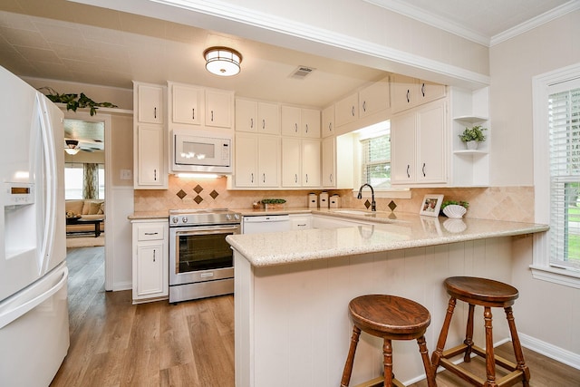 3339 Terry St, Needville, TX 77461 - kitchen with white appliances, light wood-style floors, a peninsula, healthy amount of natural light, and crown molding