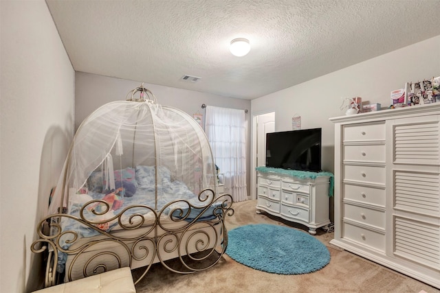 carpeted bedroom featuring a textured ceiling and visible vents