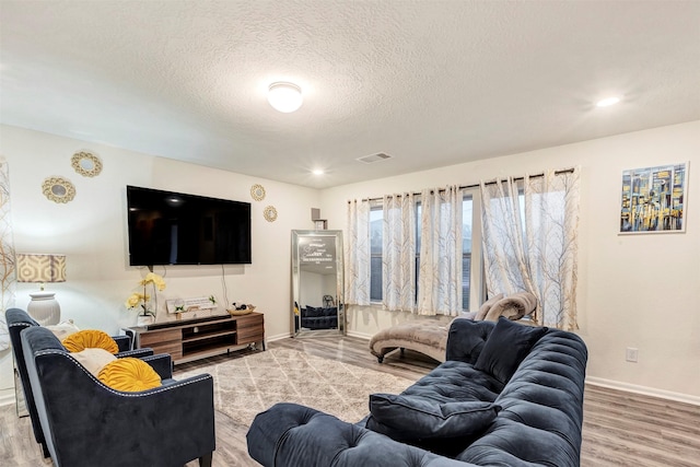 living room with visible vents, wood finished floors, baseboards, recessed lighting, and a textured ceiling