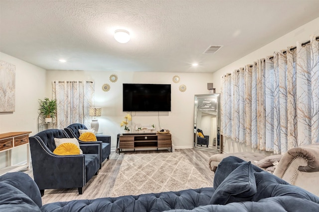 living room with a textured ceiling, recessed lighting, baseboards, wood finished floors, and visible vents