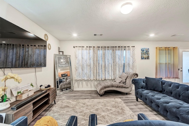 living area with a textured ceiling, wood finished floors, and visible vents