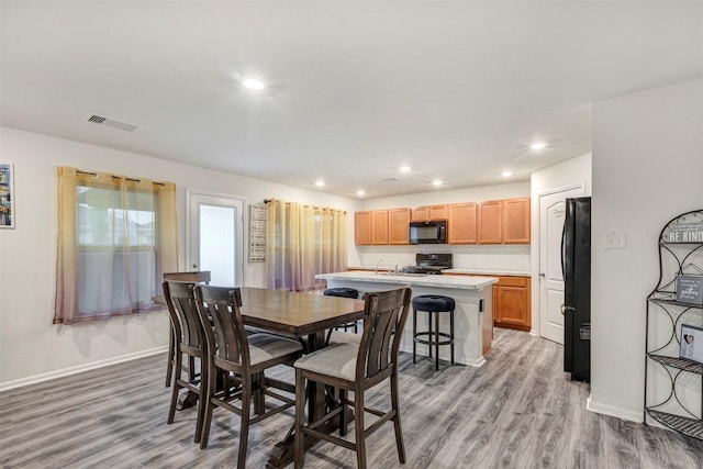 dining room with light wood finished floors, baseboards, visible vents, and recessed lighting