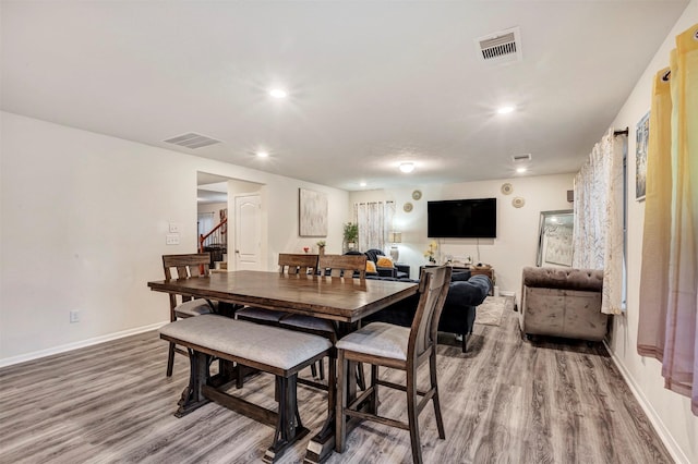 dining space with stairway, baseboards, visible vents, and wood finished floors