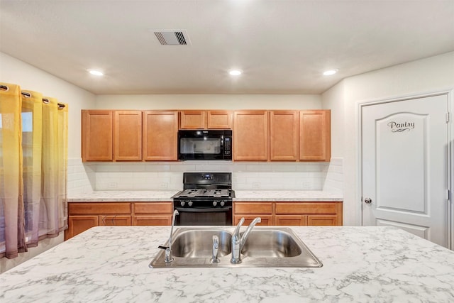 kitchen featuring a sink, light countertops, backsplash, visible vents, and black appliances