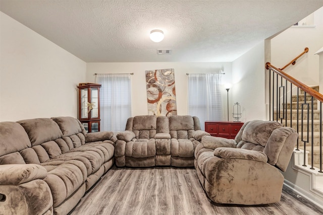 living area with visible vents, a textured ceiling, light wood-style flooring, and stairway