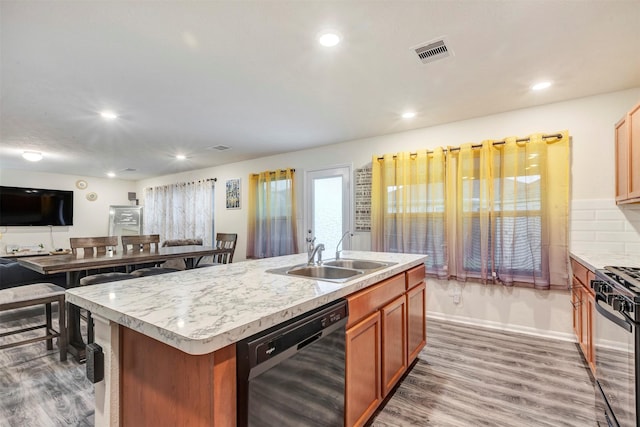 kitchen with visible vents, wood finished floors, a sink, light countertops, and black appliances