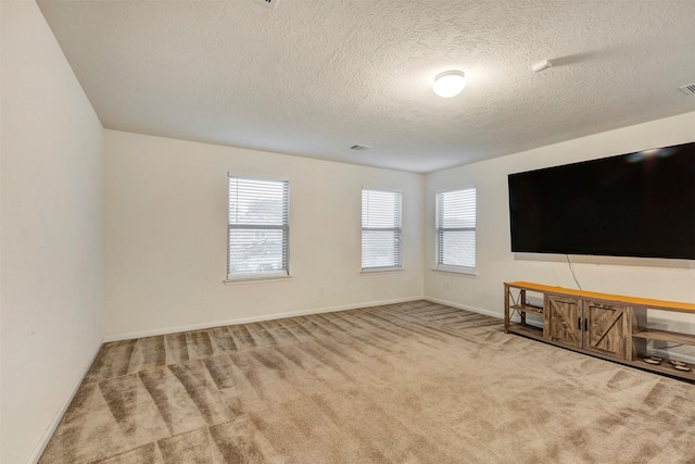 unfurnished living room with carpet floors, a textured ceiling, baseboards, and visible vents