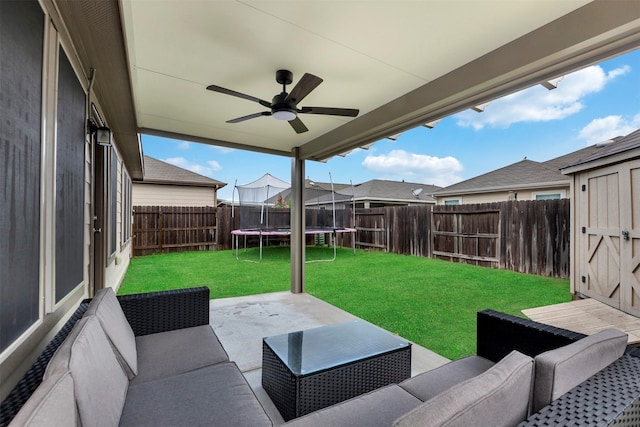 view of patio / terrace featuring ceiling fan, an outdoor living space, a fenced backyard, and a trampoline