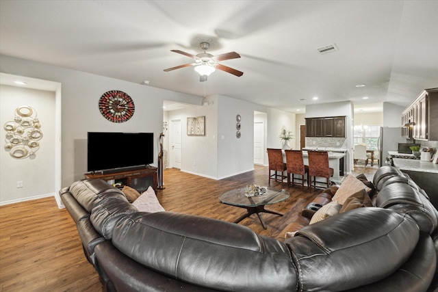 living area featuring wood finished floors, baseboards, a ceiling fan, and visible vents