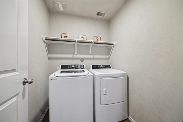 clothes washing area with visible vents, washer and clothes dryer, and laundry area