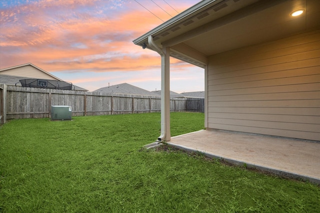 yard at dusk with a patio area and a fenced backyard
