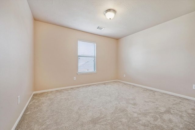 carpeted empty room featuring visible vents and baseboards