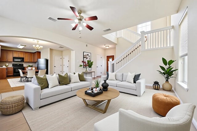 living room with a ceiling fan, visible vents, arched walkways, and stairway