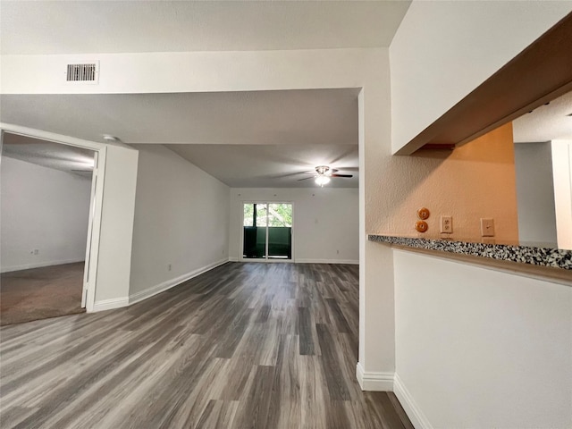 unfurnished living room with baseboards, visible vents, ceiling fan, and dark wood-style flooring
