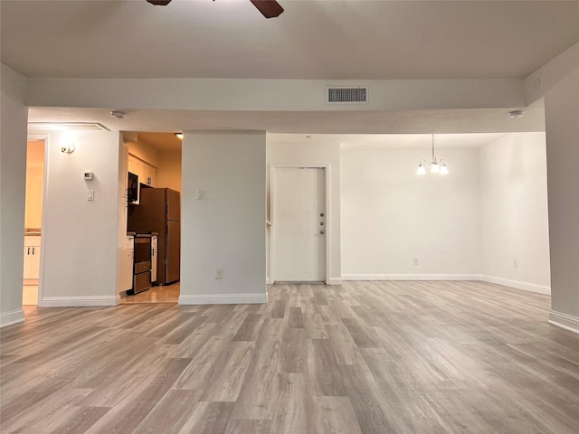 unfurnished living room featuring light wood-style flooring, visible vents, baseboards, and ceiling fan with notable chandelier