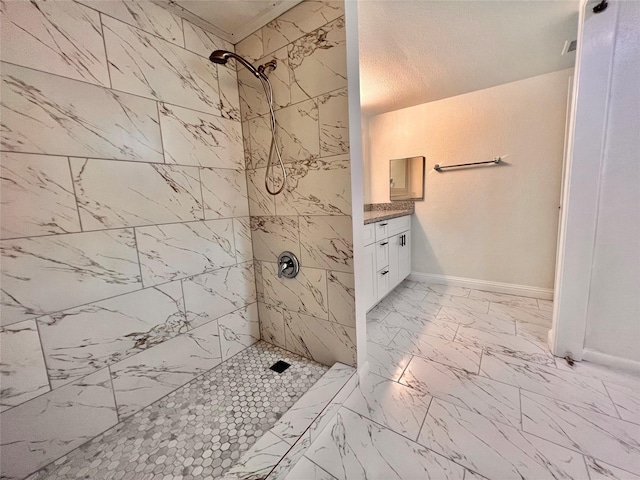 full bath featuring a tile shower, baseboards, vanity, and marble finish floor