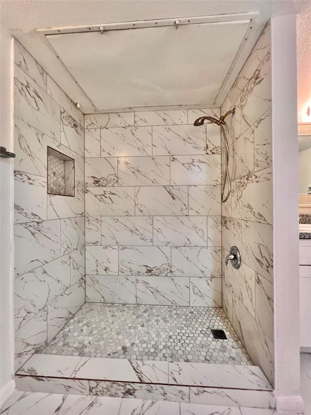 full bath with marble finish floor and a tile shower