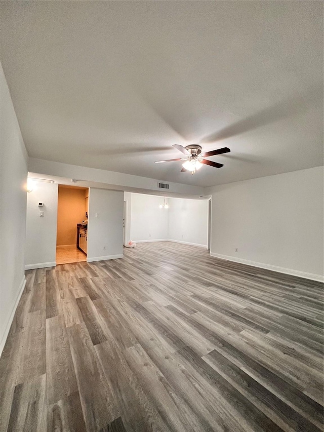 unfurnished living room featuring ceiling fan, baseboards, wood finished floors, and visible vents