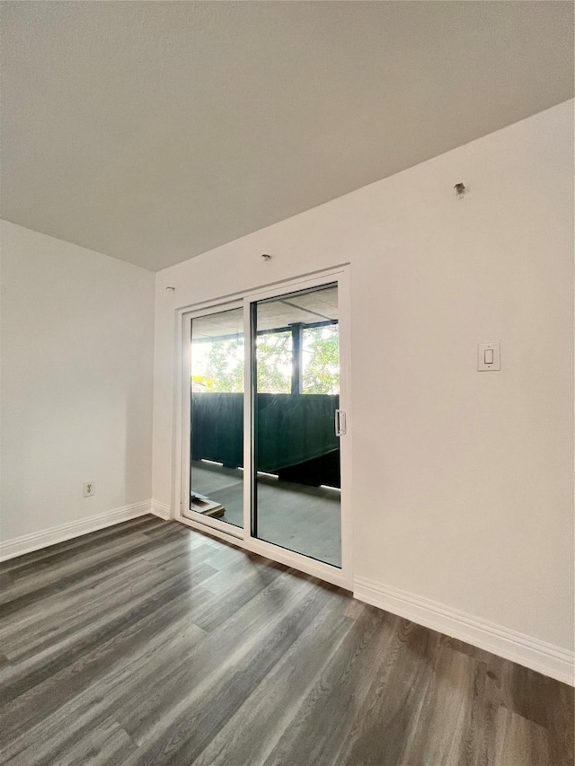 unfurnished room with baseboards and dark wood finished floors