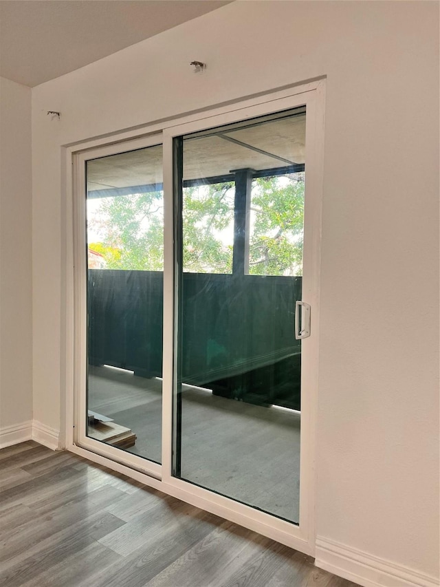 doorway with plenty of natural light, baseboards, and wood finished floors