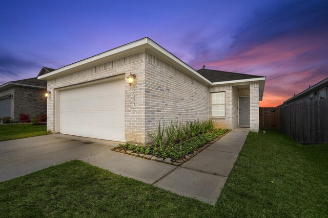 view of home's exterior featuring a lawn, driveway, fence, a garage, and brick siding