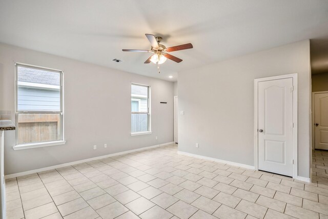 spare room featuring baseboards, visible vents, ceiling fan, and light tile patterned flooring