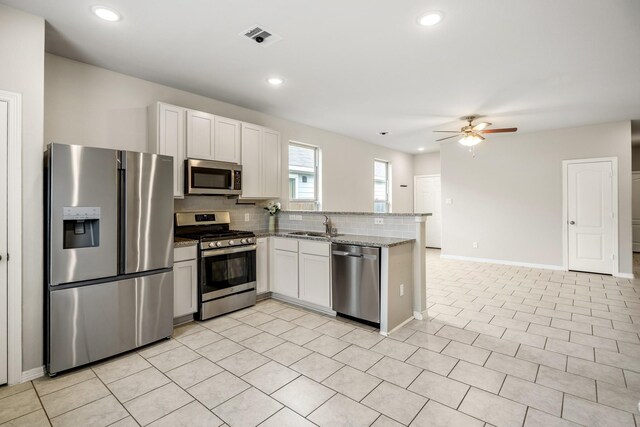kitchen with a peninsula, tasteful backsplash, visible vents, a ceiling fan, and appliances with stainless steel finishes