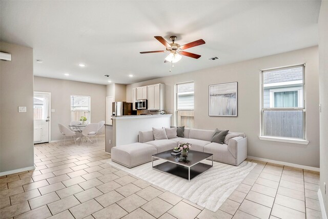 living room featuring light tile patterned floors, ceiling fan, plenty of natural light, and visible vents