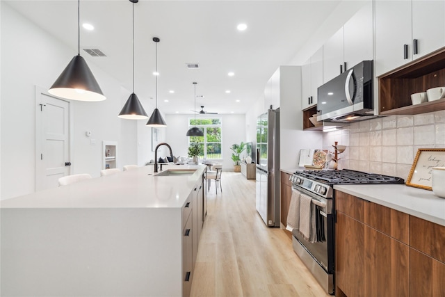 kitchen with stainless steel appliances, modern cabinets, a sink, and a spacious island