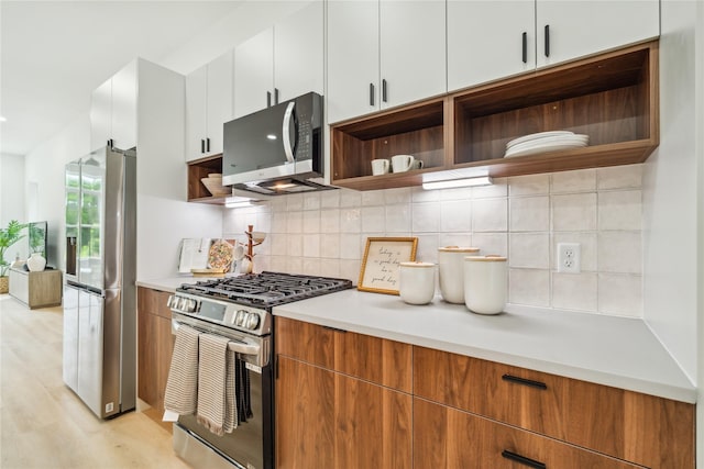 kitchen featuring open shelves, light countertops, tasteful backsplash, and stainless steel appliances