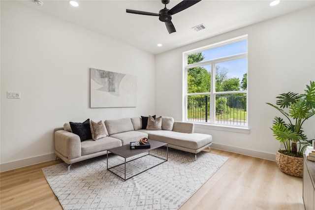 living room with baseboards, light wood-style floors, ceiling fan, and a healthy amount of sunlight