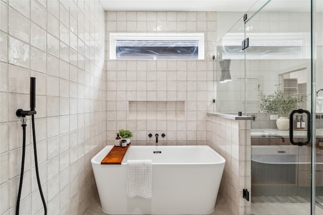 full bathroom featuring tile walls, a shower stall, and a freestanding bath