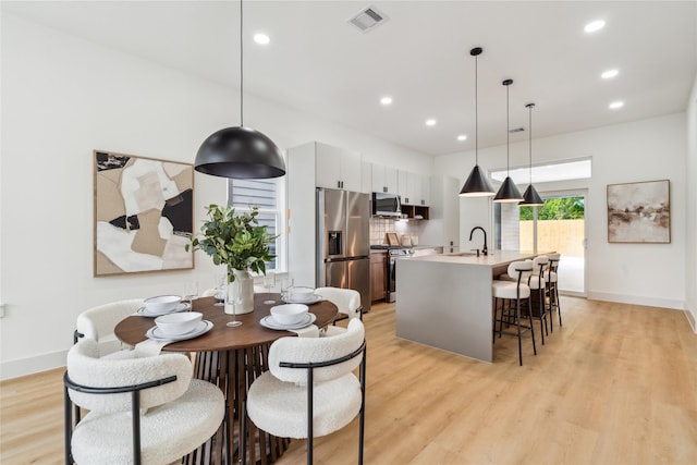 dining room with baseboards, light wood-style floors, and visible vents