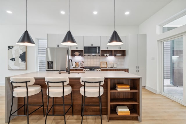 kitchen with open shelves, a sink, backsplash, and appliances with stainless steel finishes