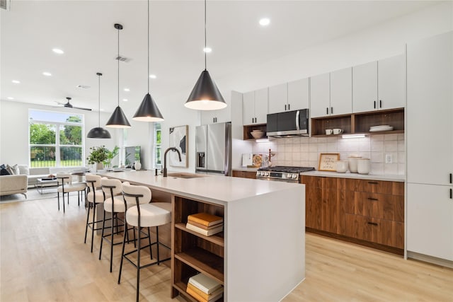 kitchen featuring open shelves, light wood-style flooring, a sink, and appliances with stainless steel finishes