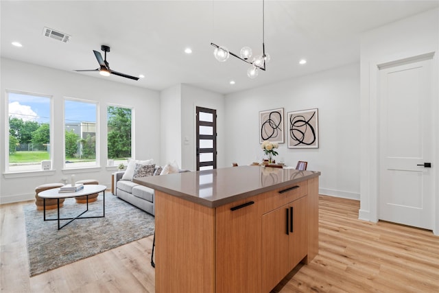 6412 Foster St, Houston, TX 77021 - kitchen featuring light wood finished floors, a center island, visible vents, and ceiling fan with notable chandelier