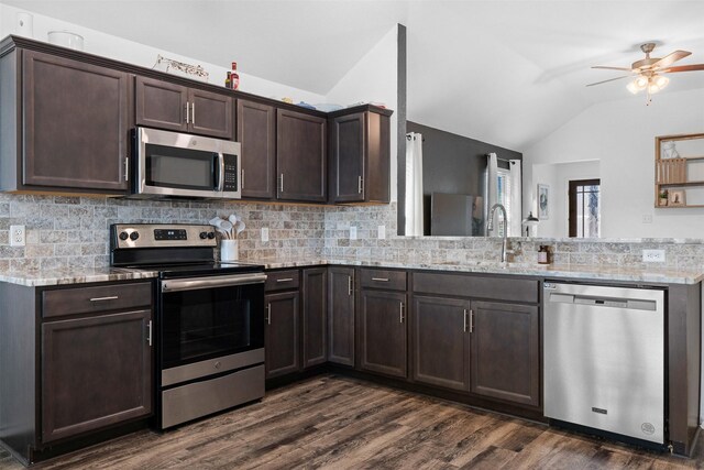 125 Dove Landing Ct, Navasota, TX 77868 - kitchen featuring stainless steel appliances, dark brown cabinets, vaulted ceiling, a sink, and decorative backsplash