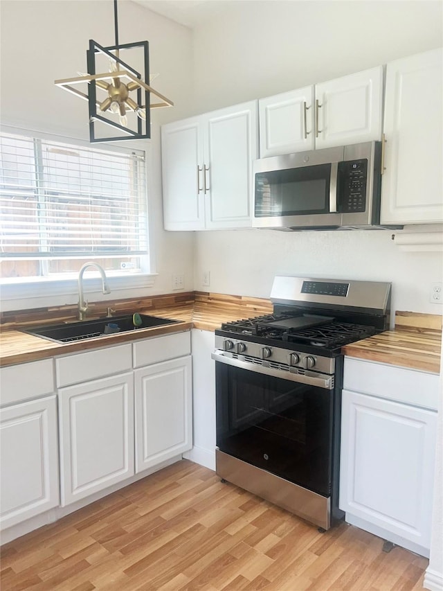 2711 N Belgravia Dr, Pearland, TX 77584 - kitchen with appliances with stainless steel finishes, light wood-type flooring, a sink, white cabinets, and butcher block counters