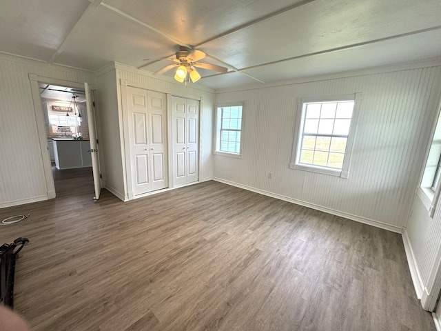 unfurnished bedroom with ceiling fan, baseboards, wood finished floors, and a closet