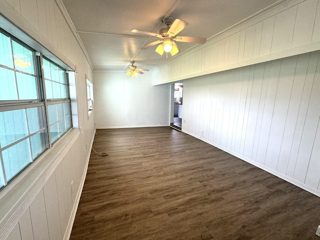 empty room featuring ceiling fan, baseboards, ornamental molding, and dark wood finished floors