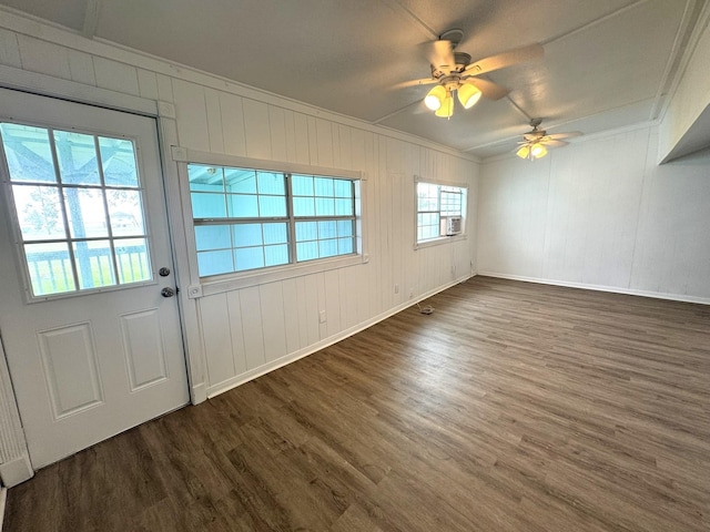 interior space with baseboards, wood finished floors, ceiling fan, and ornamental molding