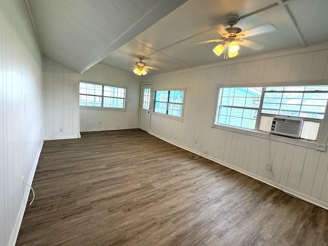 unfurnished room with wood walls, wood finished floors, a ceiling fan, cooling unit, and baseboards