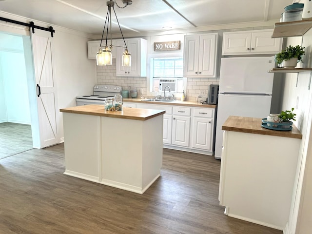 kitchen with a barn door, white appliances, butcher block countertops, tasteful backsplash, and white cabinetry