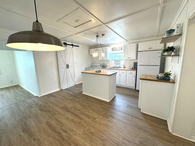kitchen with a barn door, a sink, white appliances, butcher block counters, and dark wood finished floors