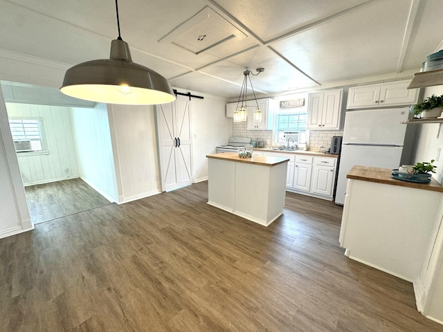 kitchen with a barn door, butcher block countertops, a sink, and white appliances