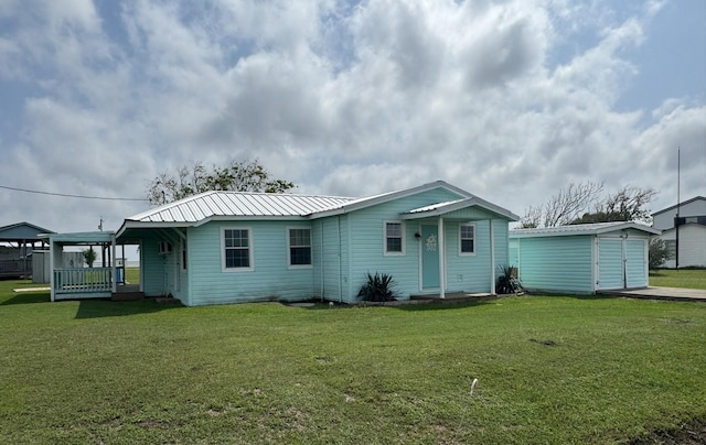 rear view of house with a lawn, an outbuilding, and metal roof