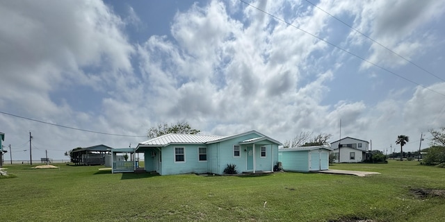 back of property featuring a storage shed, a yard, an outbuilding, and metal roof