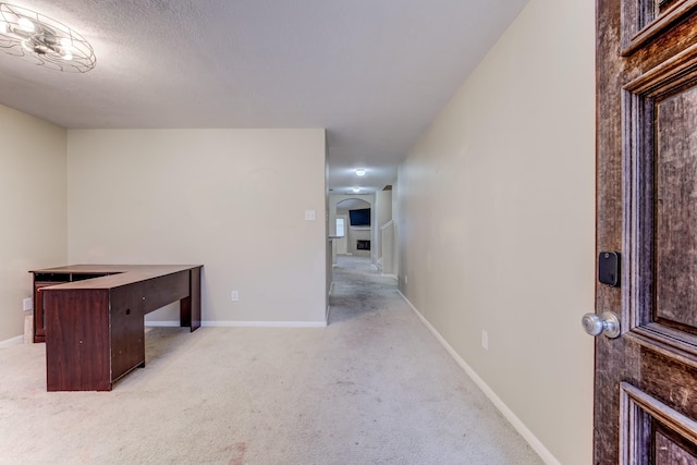 unfurnished office featuring baseboards, arched walkways, and light colored carpet