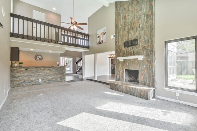 unfurnished living room with carpet, stairway, baseboards, a fireplace, and high vaulted ceiling