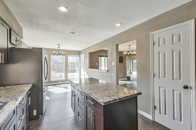 kitchen with dark wood-style floors, a notable chandelier, a textured wall, and visible vents